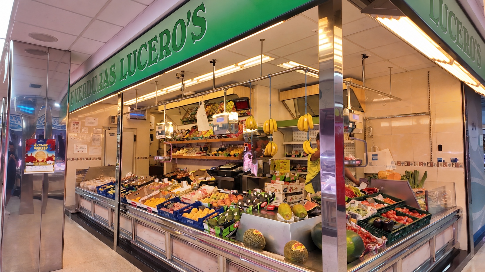 Vista del puesto de Frutería Lucero’s, con frutas y verduras; rótulo actualizado digitalmente